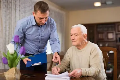 Man helping senior citizen go through paperwork