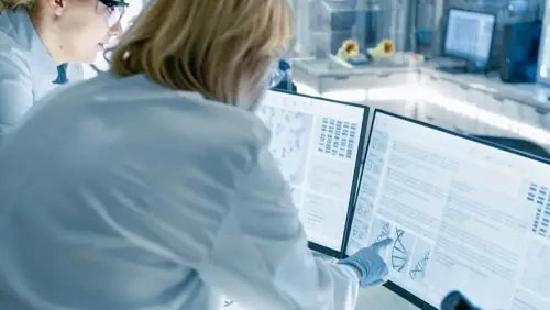 Two researchers looking at two large monitors that are side by side