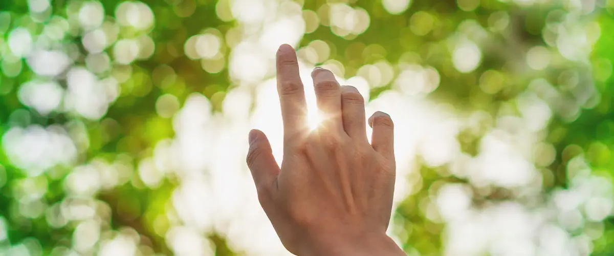 Hand reaching out towards the sun