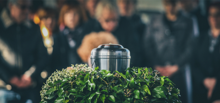 Close up of an urn on an altar with mourners in the background