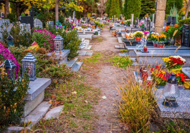 Path winding through a cemetery with floral arrangements on the graves