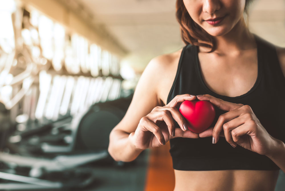 Woman in gym holding a red wooden heart in her hands